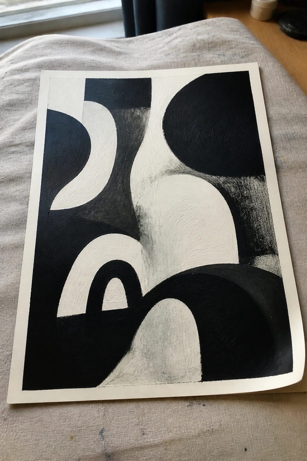Abstract black and white painting with curved shapes on textured beige fabric