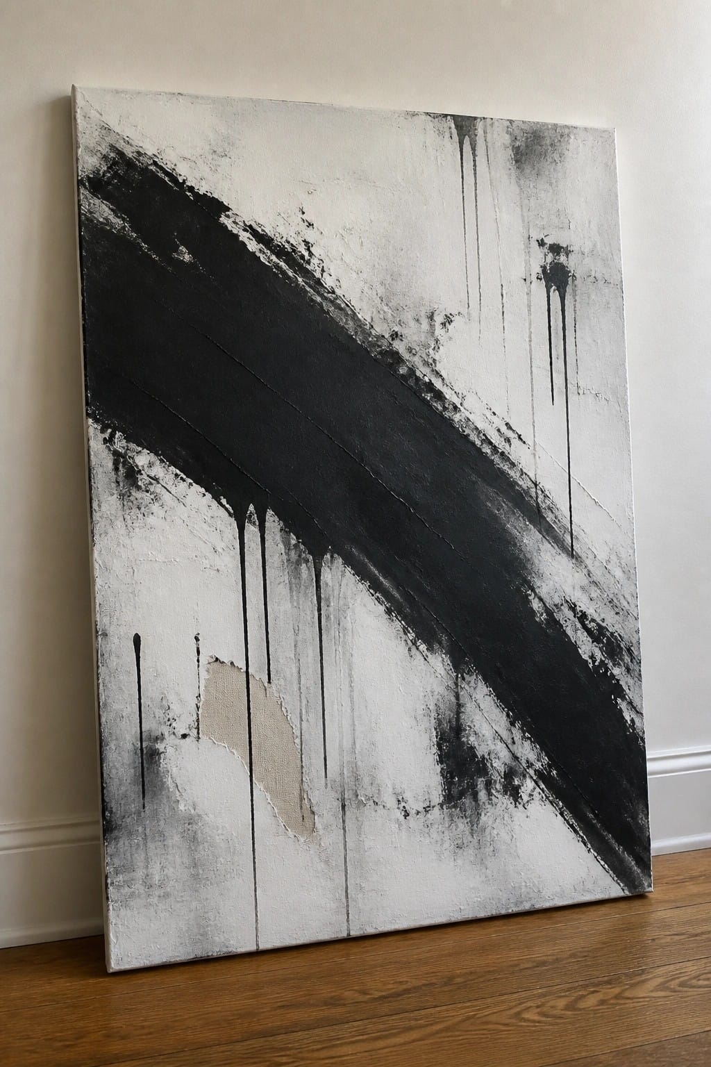 Abstract black-and-white painting with diagonal strokes and drips leaning on wooden floor against wall