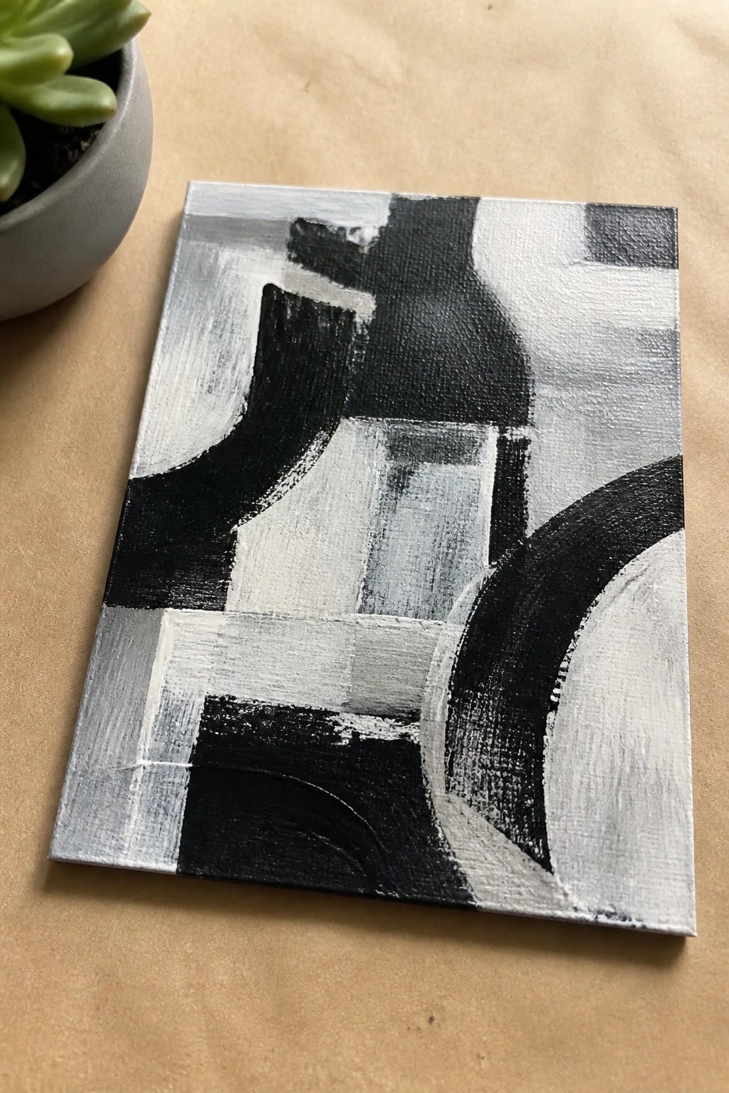 Abstract black white gray painting on canvas beside potted green succulent