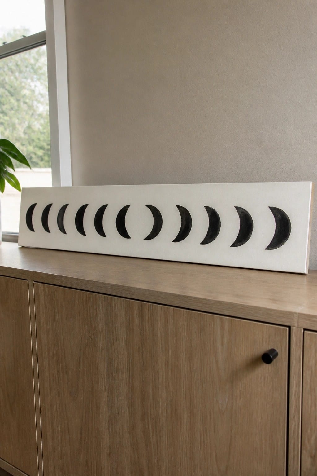 White rectangular board with black moon phases on wooden cabinet