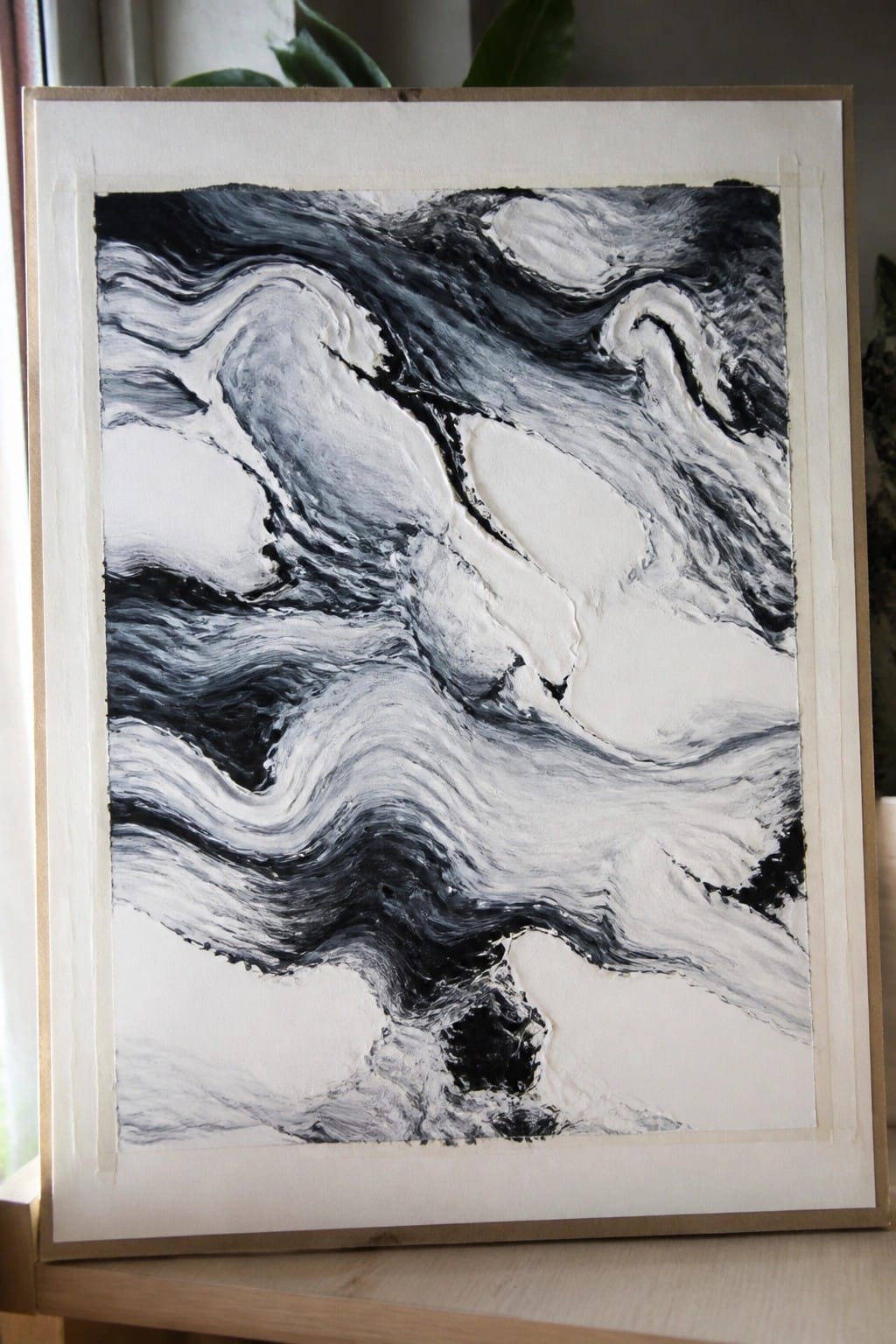 Black and white abstract painting with swirling thick impasto textures in a frame