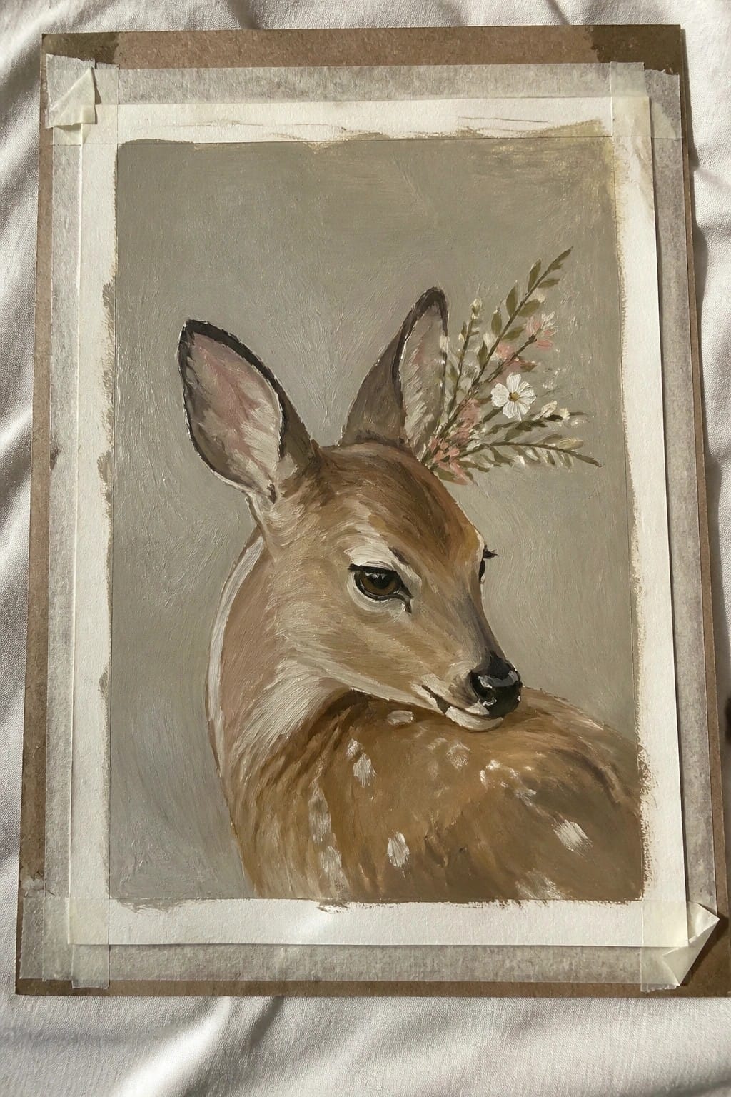Painting of fawn with floral sprig on gray background, taped to brown paper