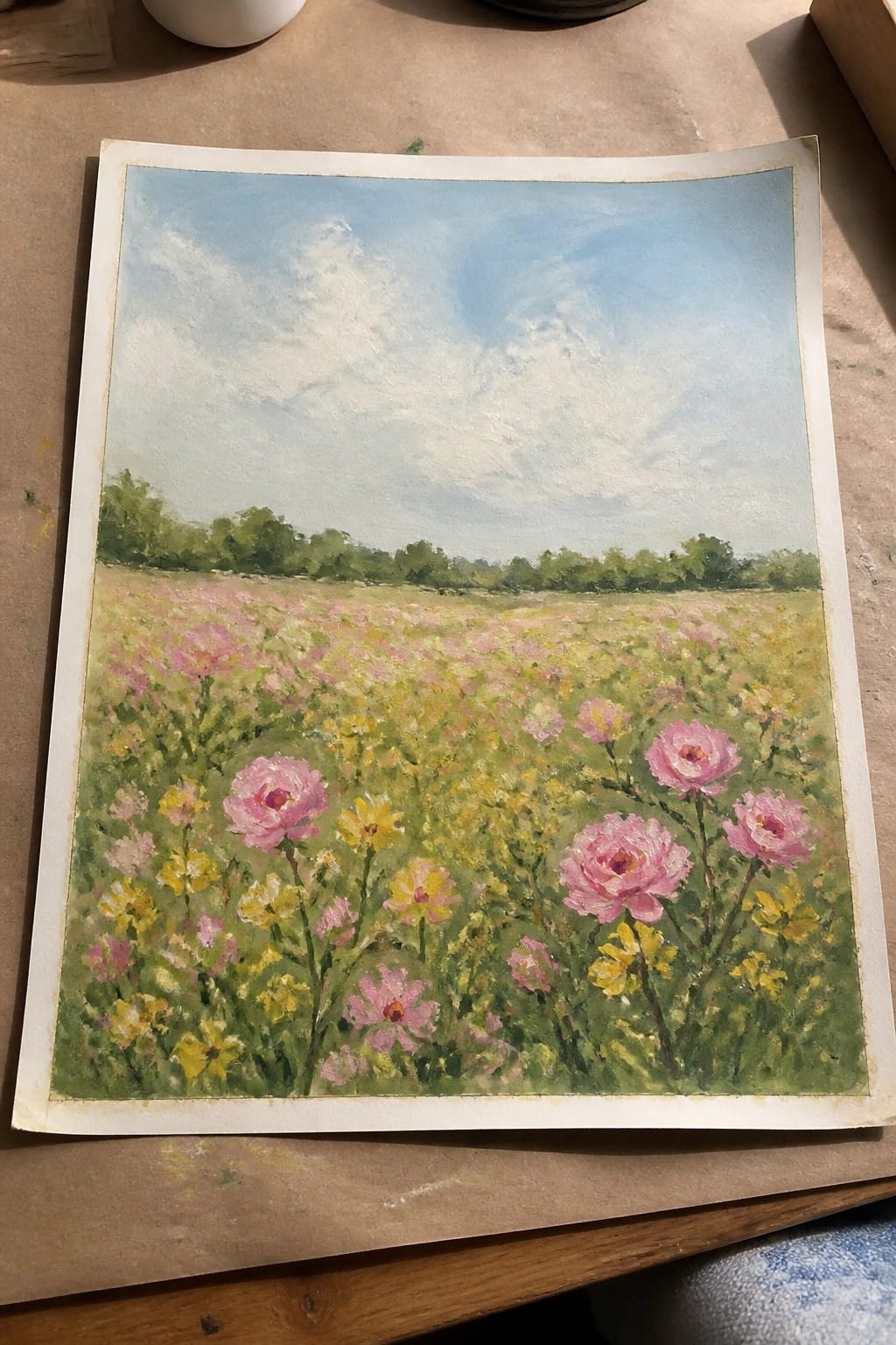 Meadow painting with pink roses, yellow wildflowers, green field, and blue cloudy sky.