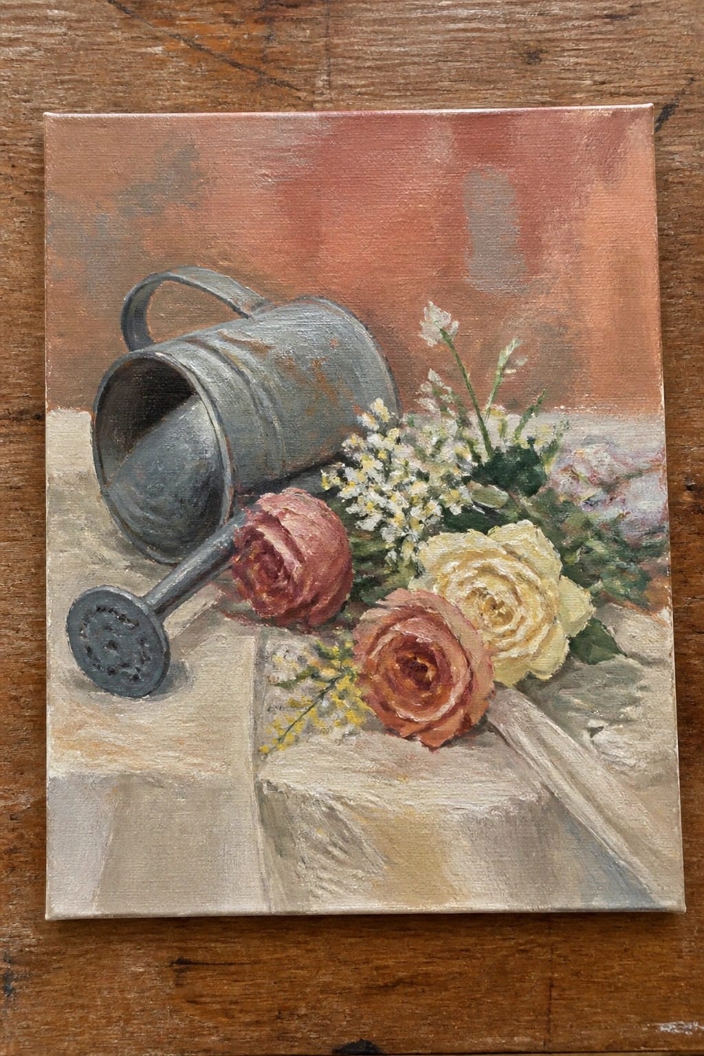 Still life with tipped gray watering can and pink yellow roses on table