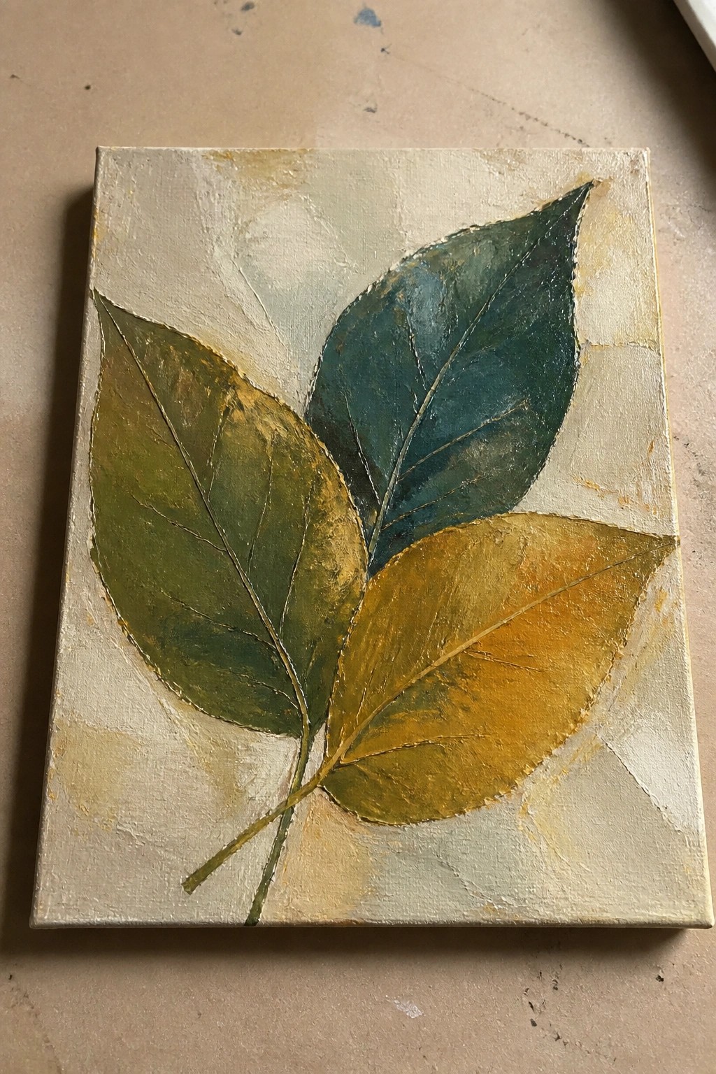 Textured painting of three leaves in green, teal, and gold on beige canvas.