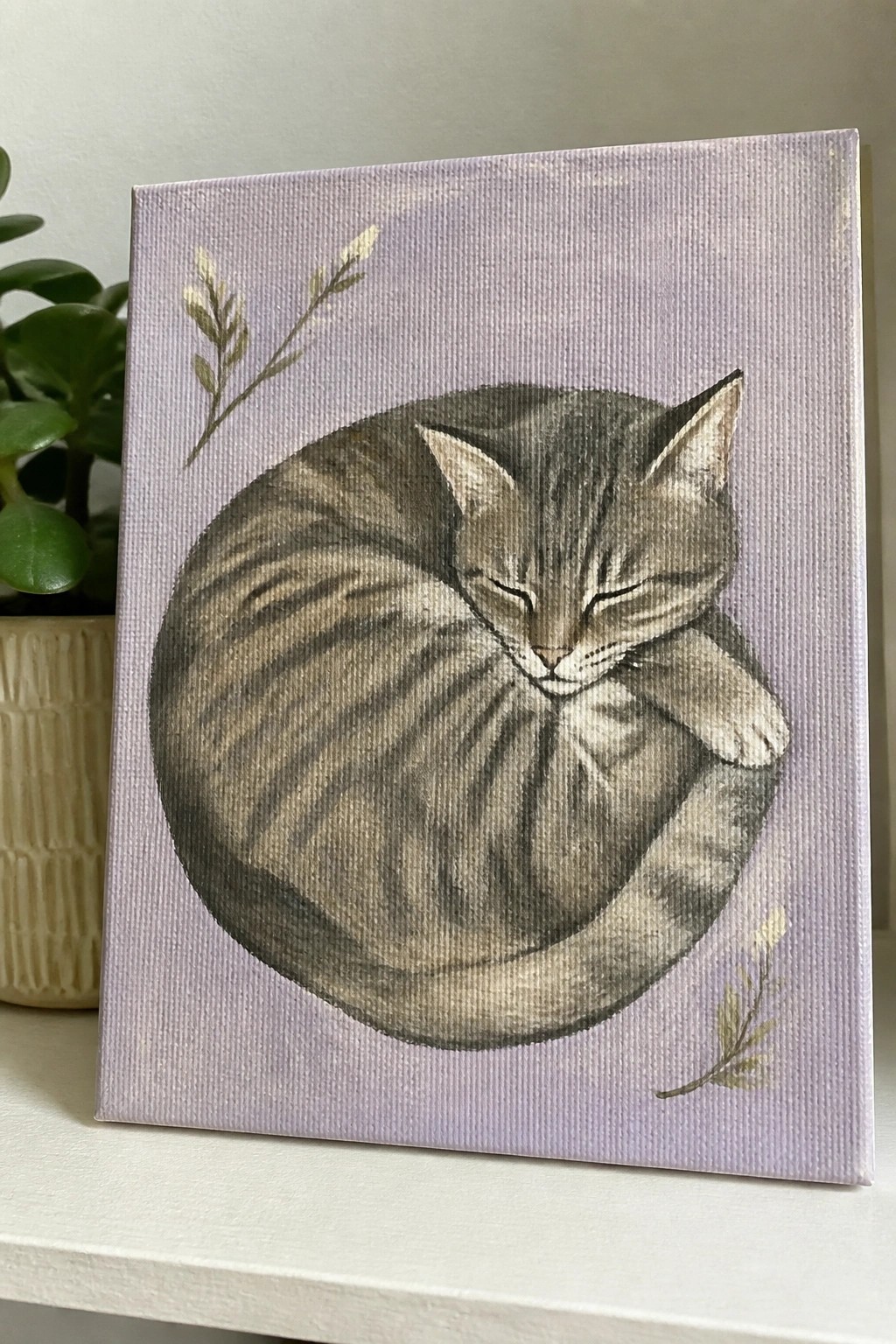 Painting of sleeping gray tabby cat curled on lavender canvas with gold leaves