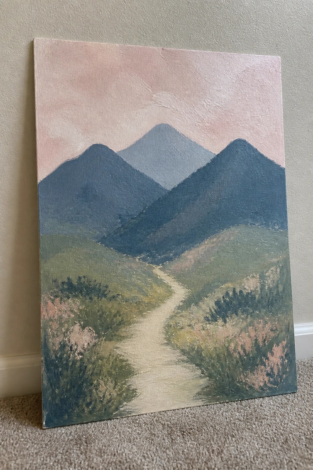 Canvas painting of winding path through green hills to layered blue mountains under pink sky