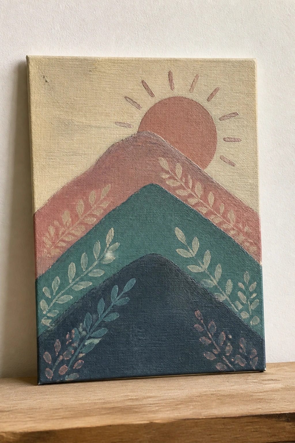 Layered mountains in teal, rust and navy with sun and leaf motifs on canvas