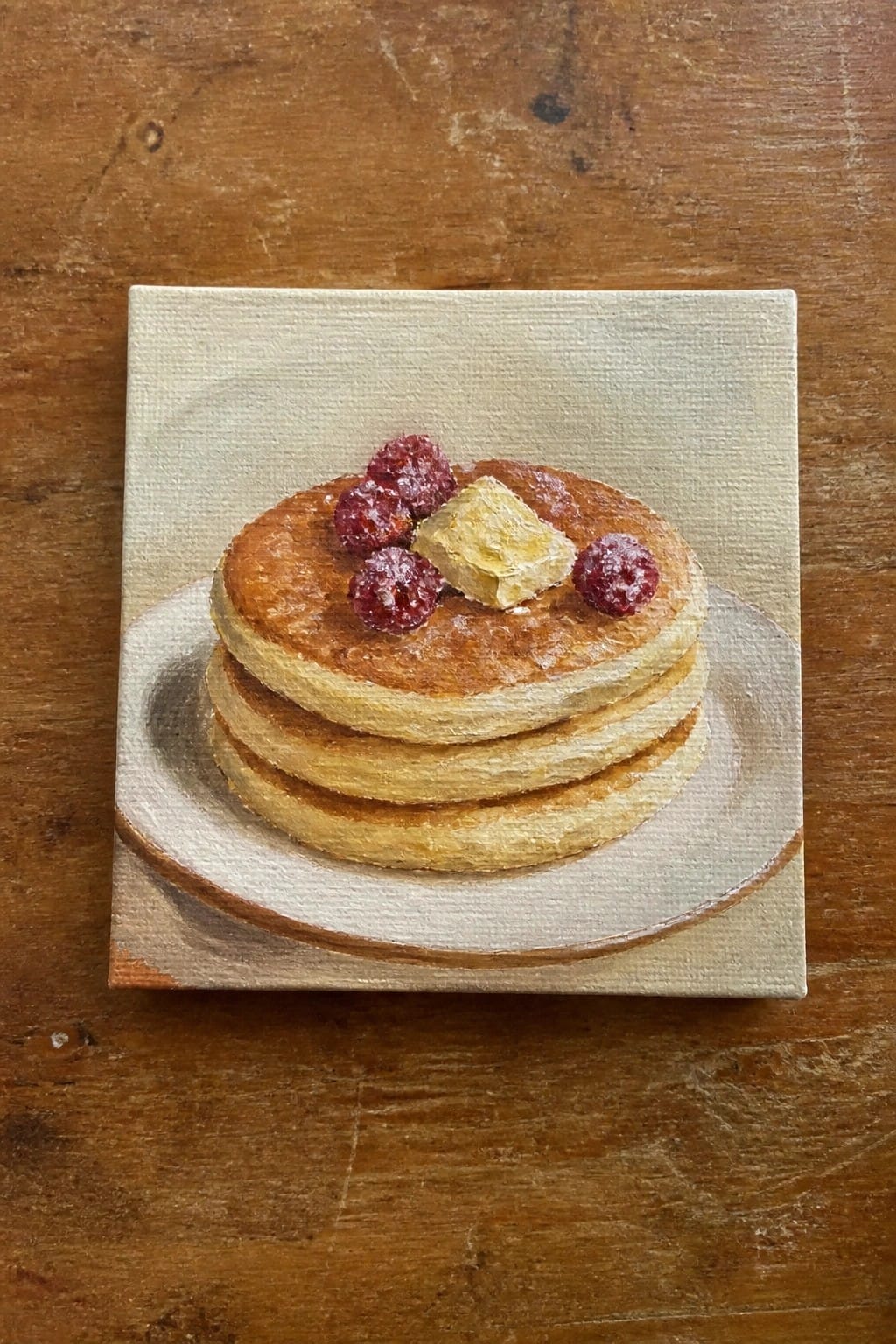 Stack of pancakes topped with butter and raspberries on plate, oil painting on canvas.