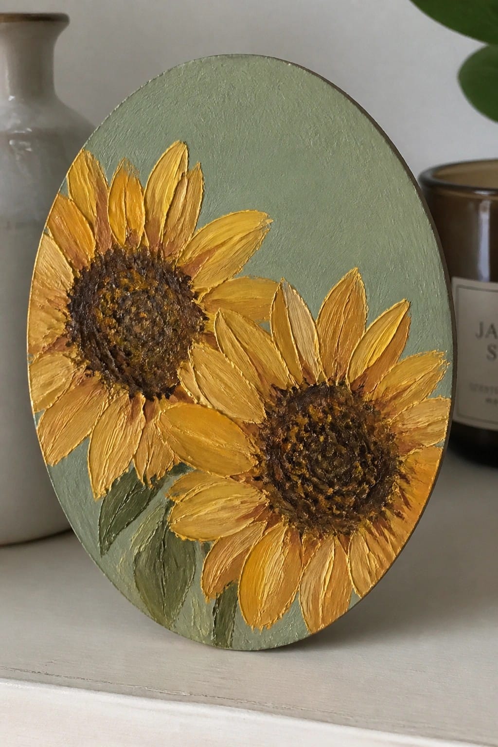 Oval canvas with two yellow sunflowers and brown centers on green background