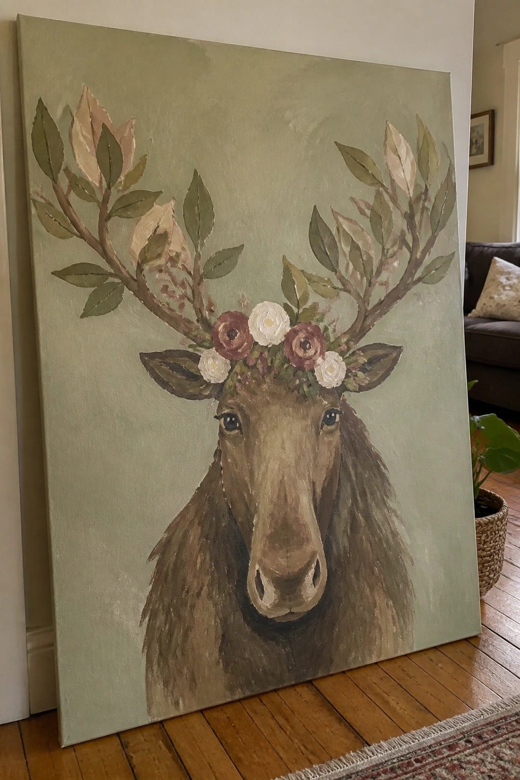 Moose head painting with floral antlers against a sage green canvas in a room