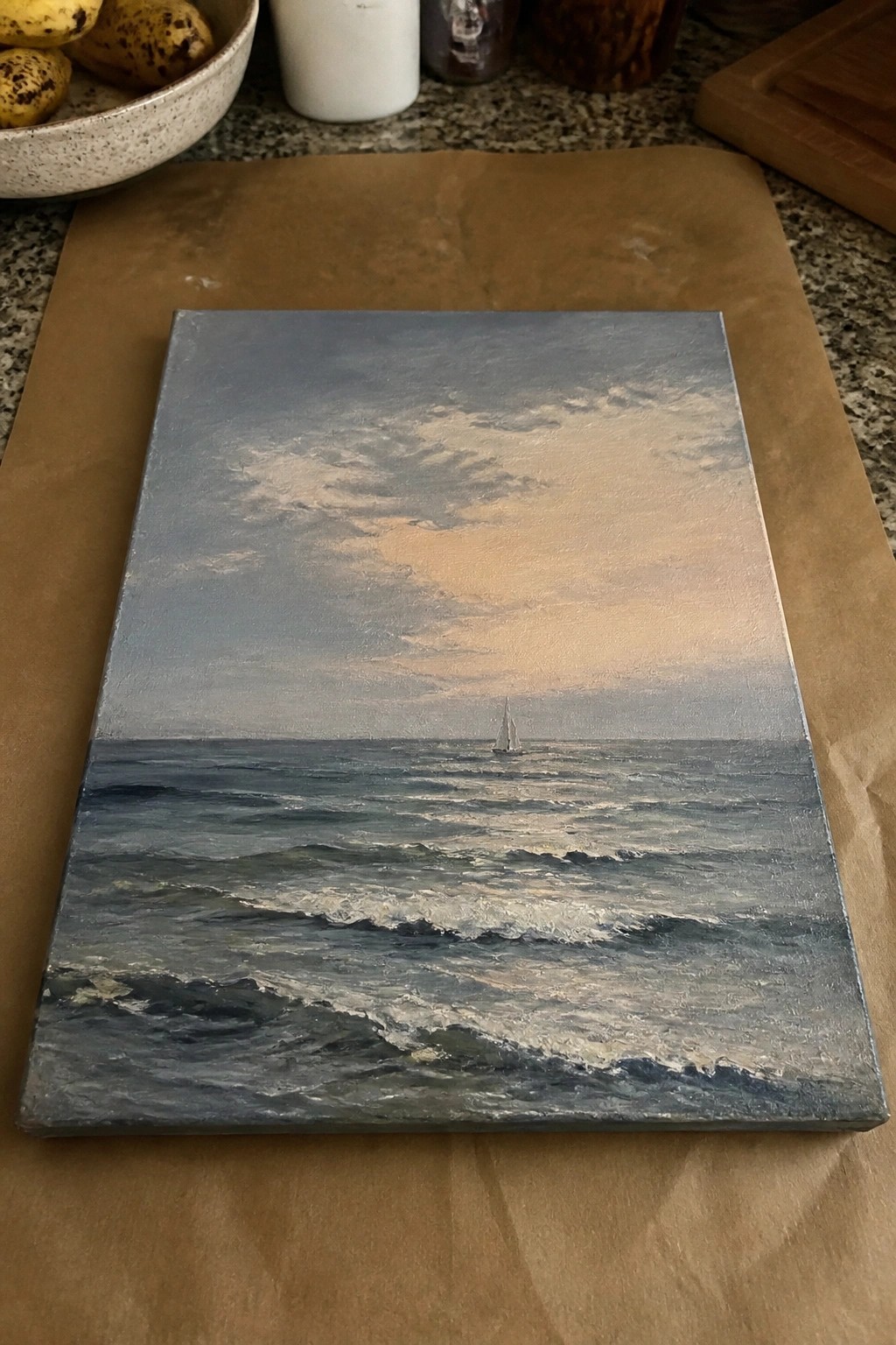 Painting of choppy sea with sailboat under pink-tinged clouds on brown paper