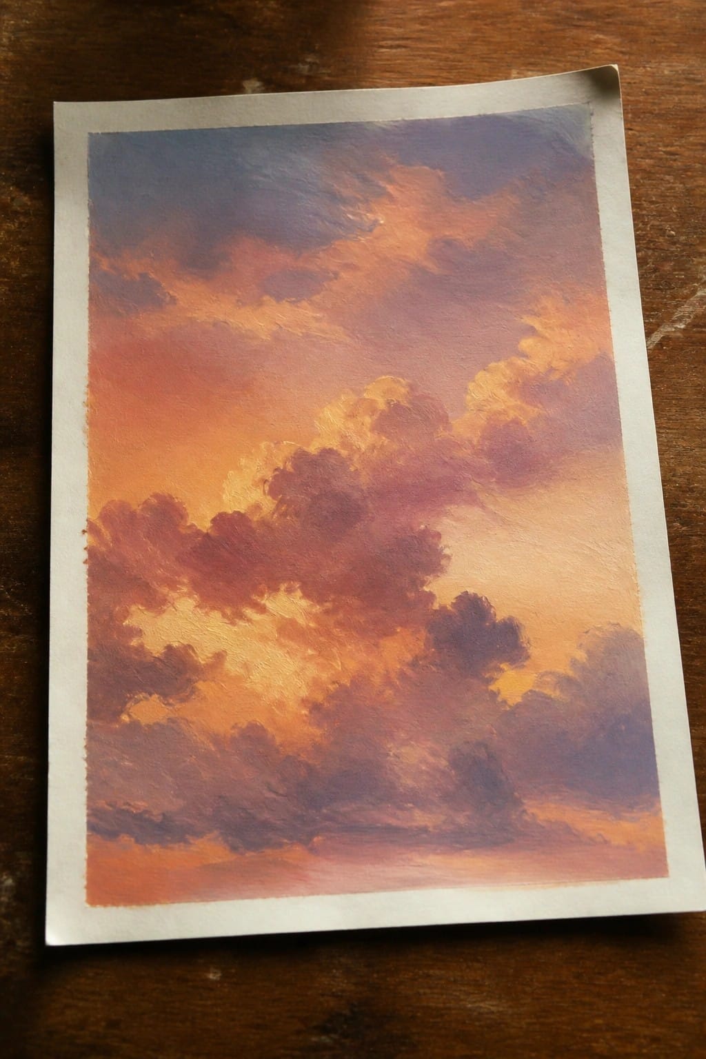 Vibrant painting of sunset clouds in glowing orange, pink, and purple on wood