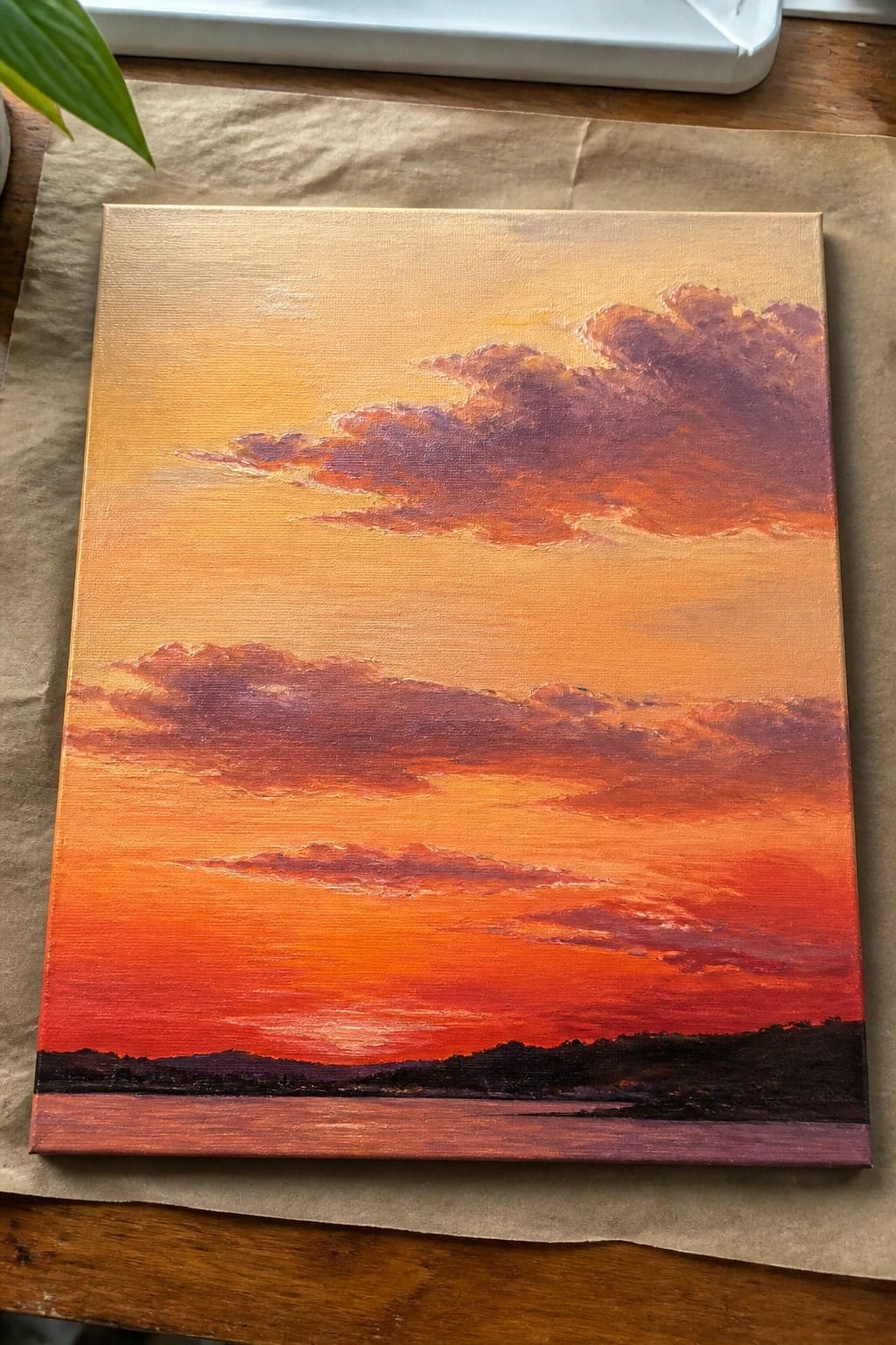 Vibrant oil painting of orange-red sunset with purple clouds over dark silhouetted hills and water.