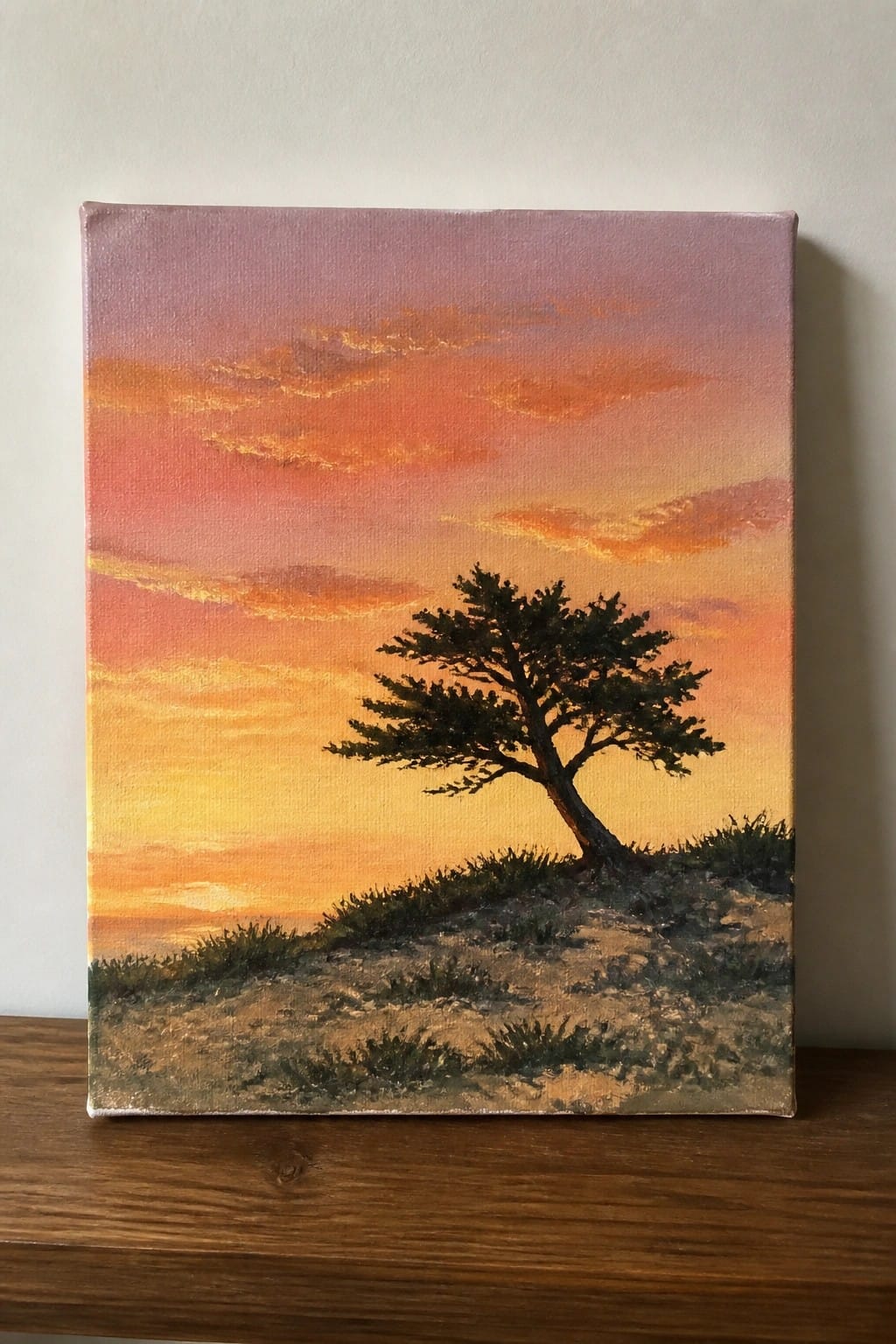 Oil painting of a lone dark tree on a grassy hill under a pink-to-orange sunset sky with soft clouds.