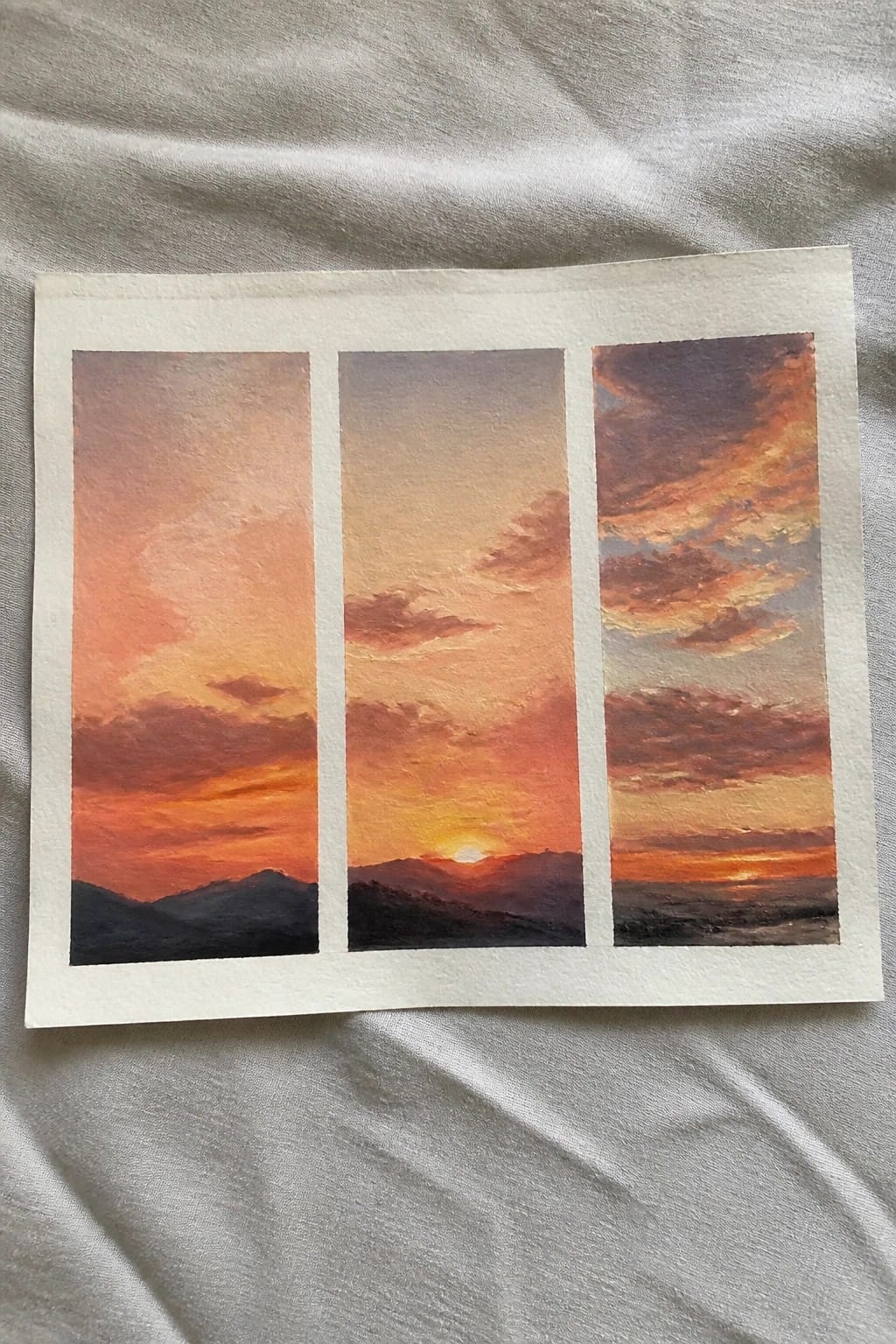 Watercolor triptych of sunset over mountains with orange red clouds and hills