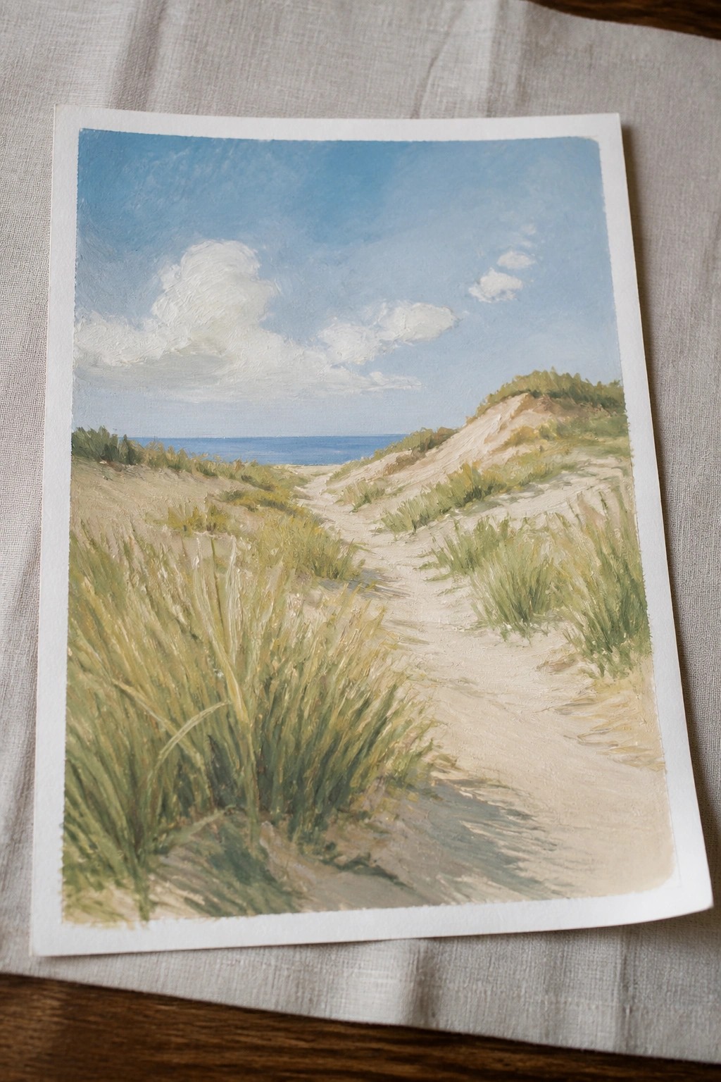 Landscape painting of a sandy path winding through grassy dunes to the blue ocean.