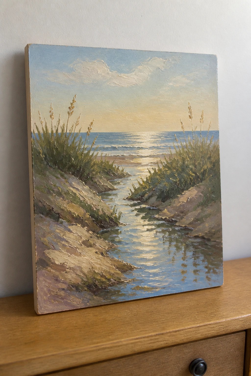 Seascape painting of stream winding through grassy dunes to sunlit ocean.