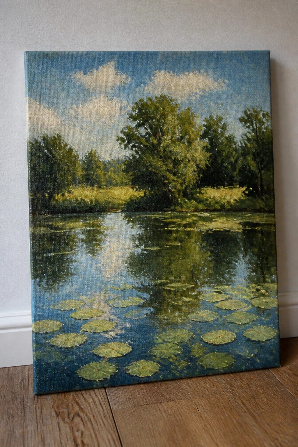 Oil painting of pond with green lily pads, tree reflections under blue cloudy sky