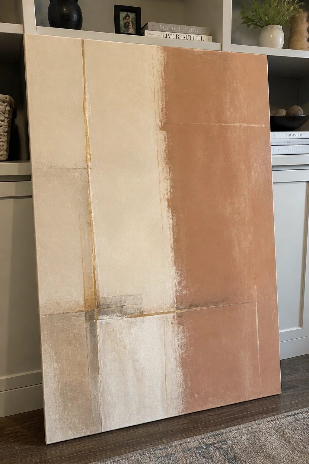 Abstract painting with beige and terracotta panels leaning against white shelves
