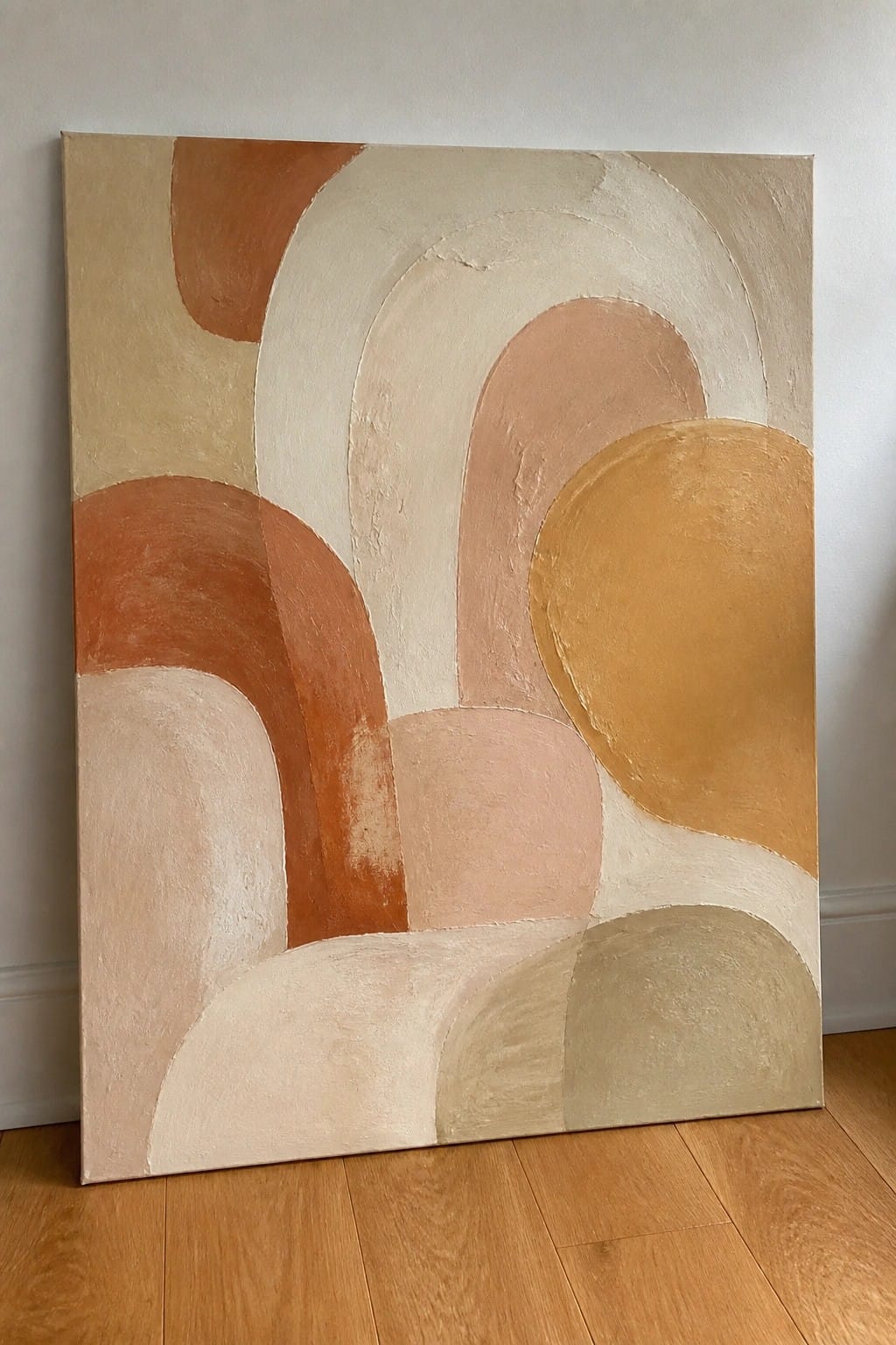 Abstract painting with overlapping curved shapes in terracotta, beige, and ochre leaning on wall