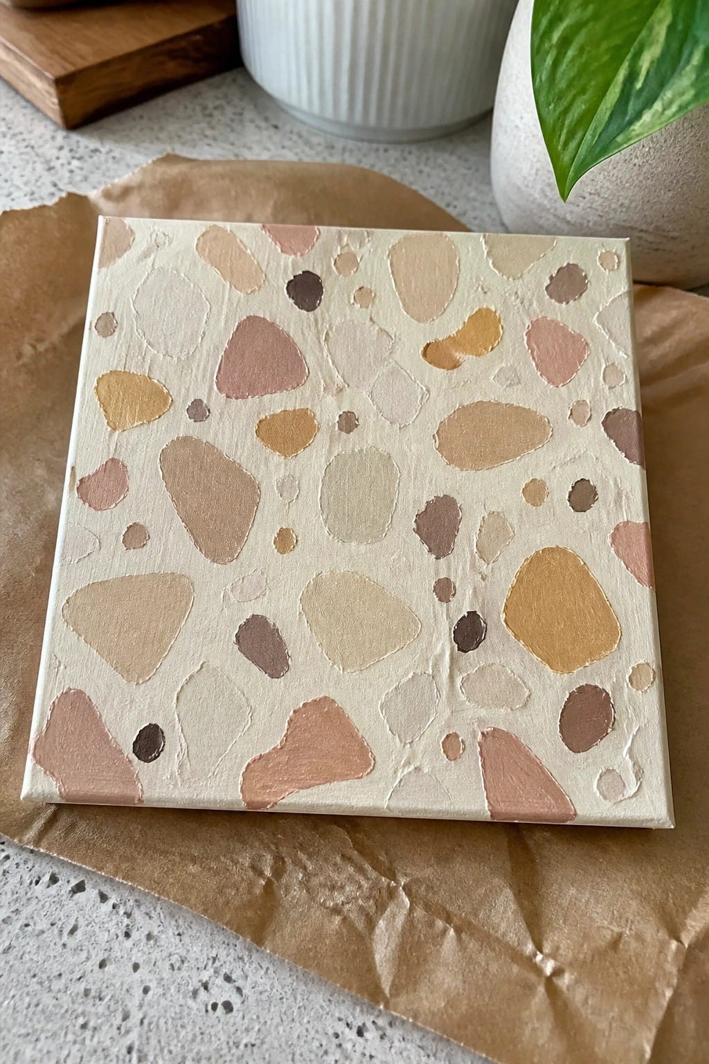 Abstract canvas with irregular pebble shapes in neutral beige, pink, and brown tones