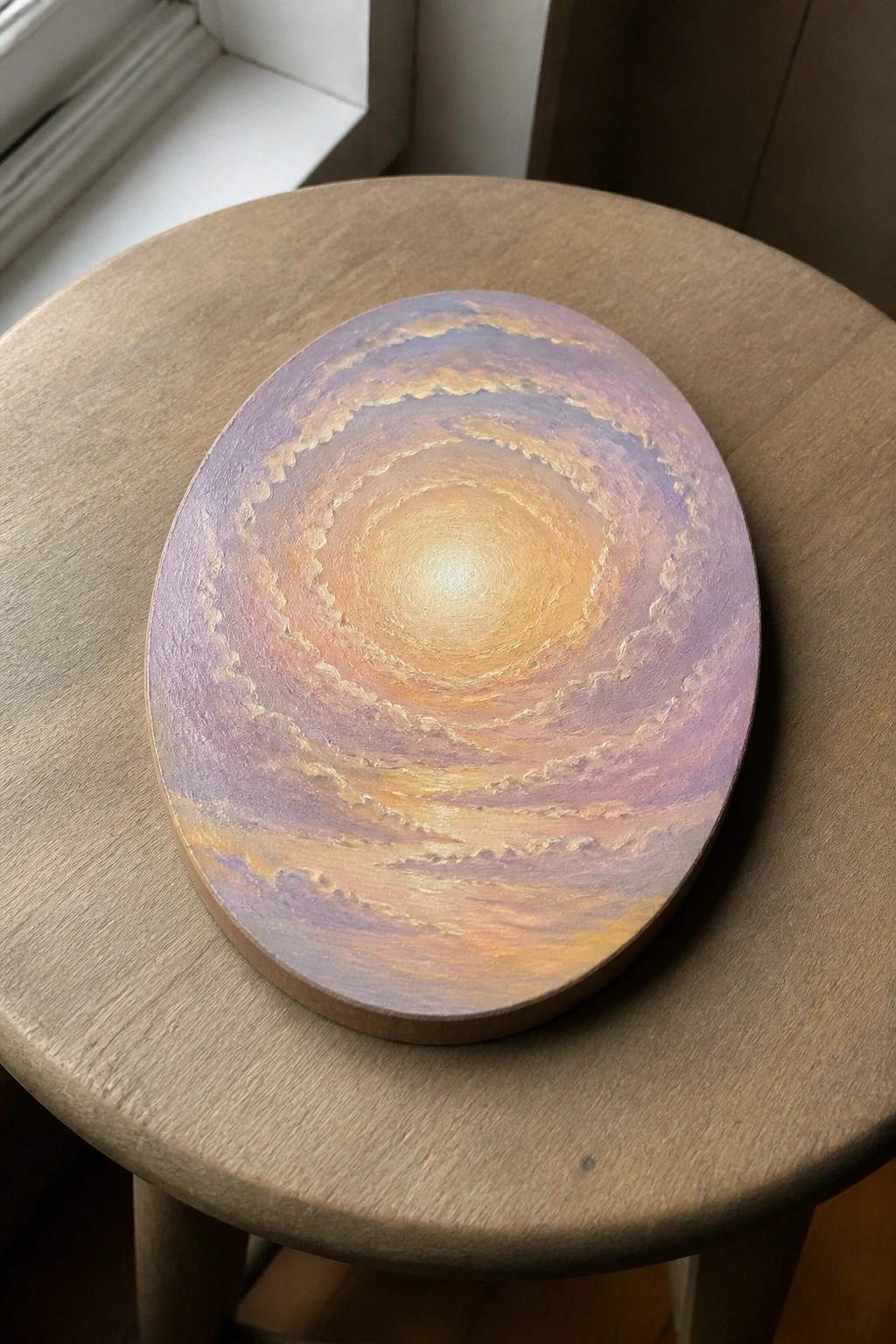 Circular painting of swirling purple and orange clouds with glowing center on wooden stool