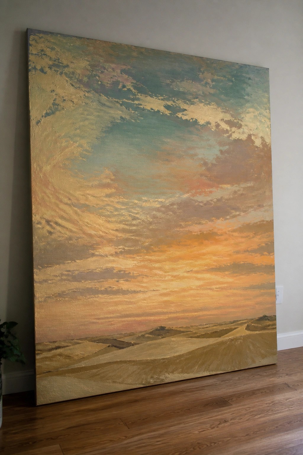 Large painting of vibrant sunset over rolling dunes leaning against wall