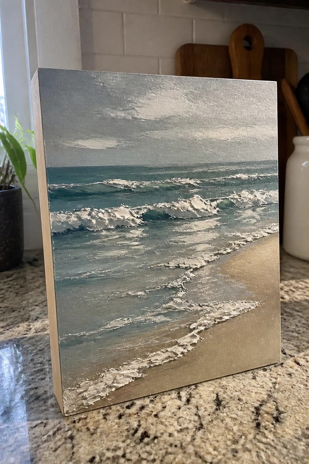 Textured seascape painting of teal waves breaking on a sandy beach on counter