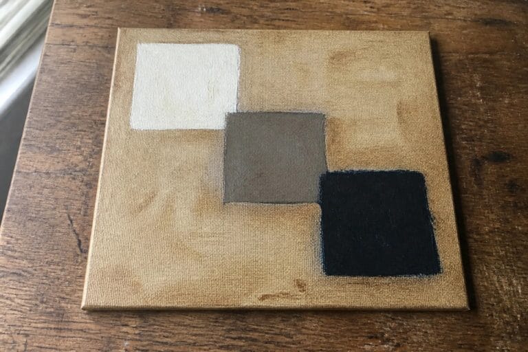 18 Foolproof Oil Painting Practice Exercises For Beginners A small oil painting on canvas with three squares in white, gray, and dark blue placed on a beige background.