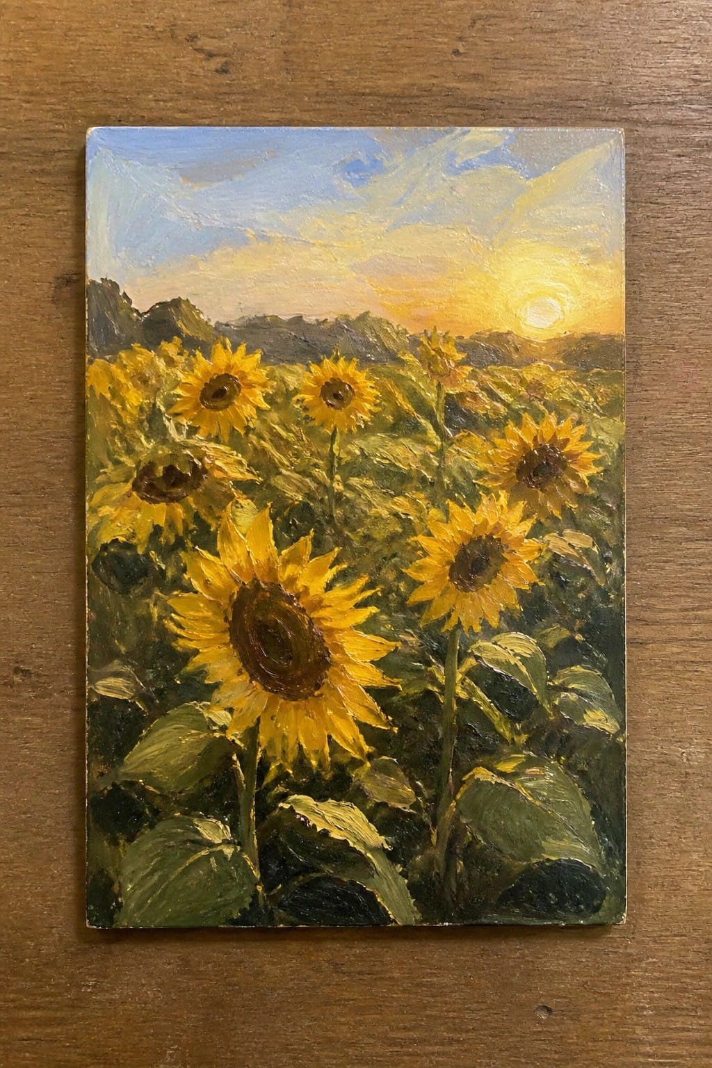 Oil painting of yellow sunflowers in a green field under a vibrant sunset sky.