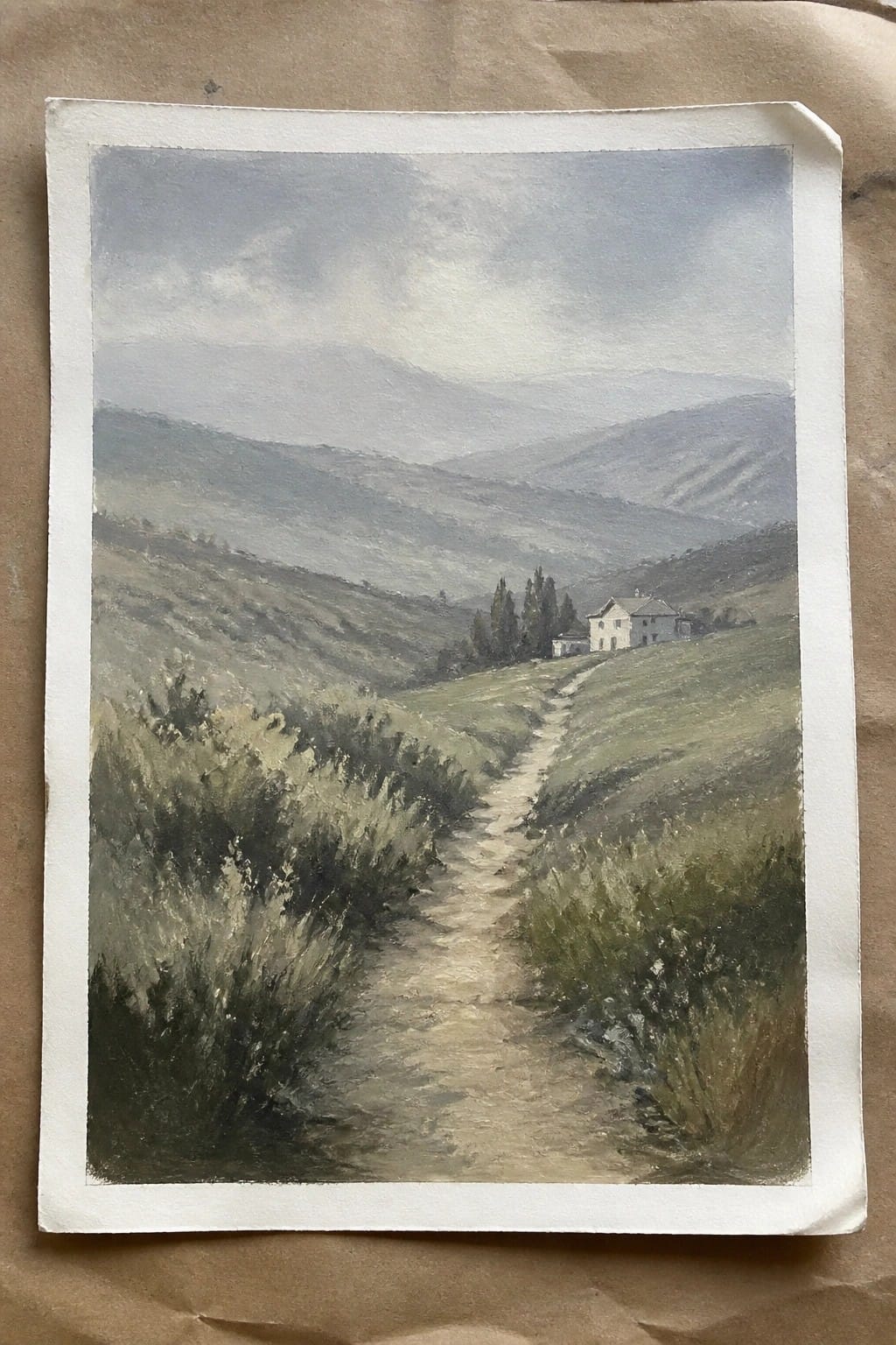 Watercolor landscape of winding path through green hills to white house with misty mountains.