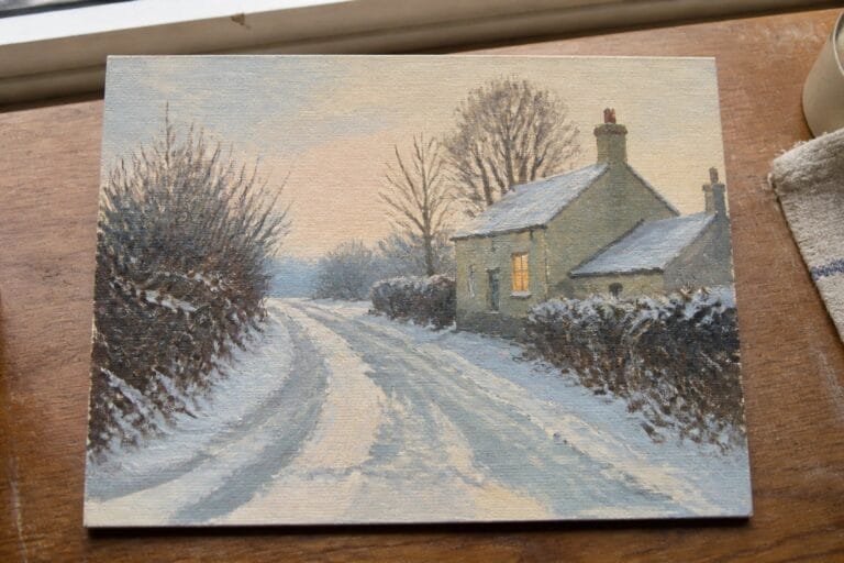Snow-covered cottage with glowing window beside winding snowy path at dusk