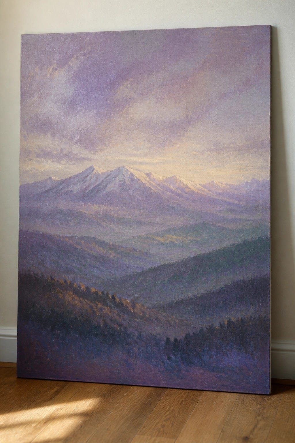 Large purple mountain landscape painting with snow peaks leaning on wall above floor