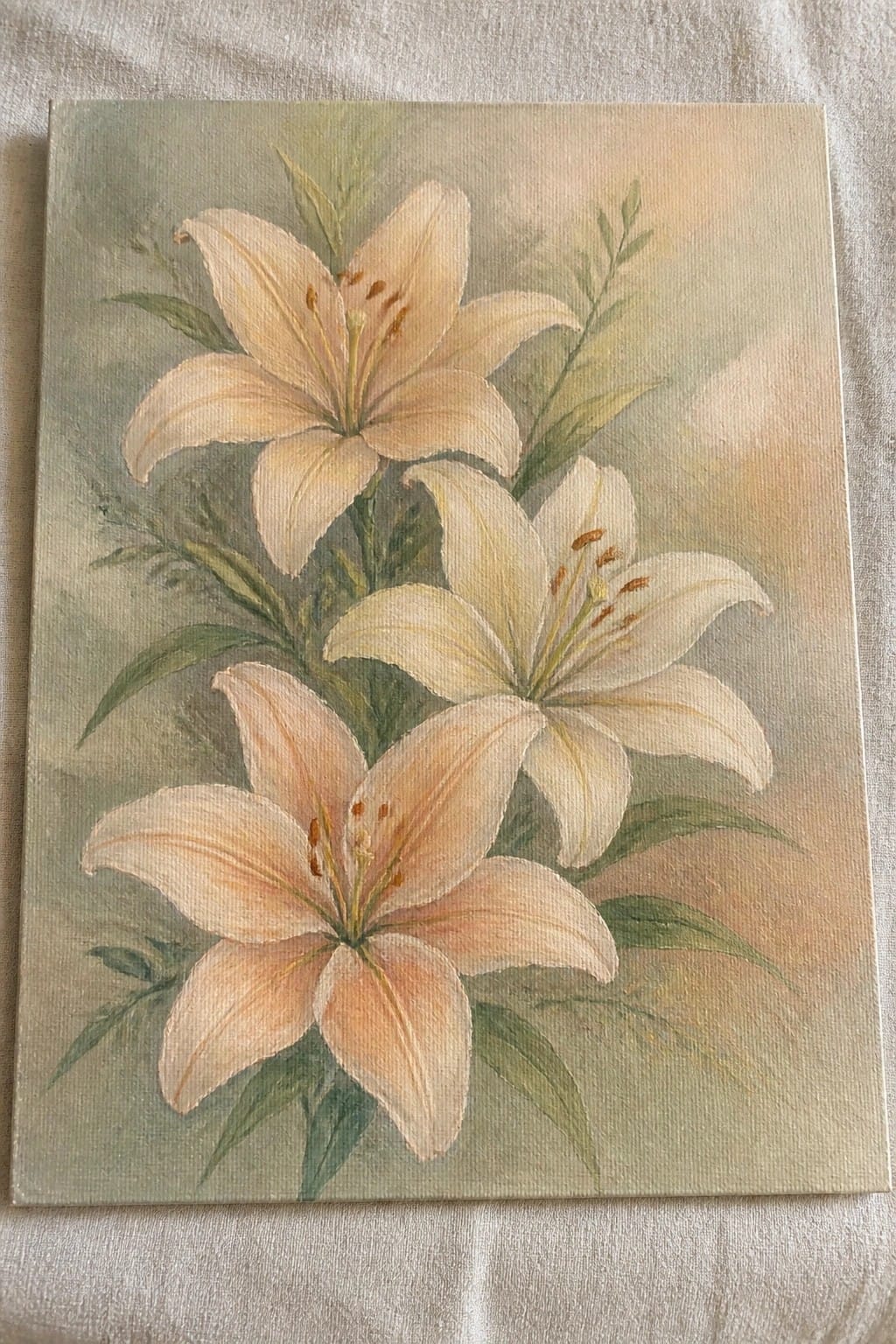 Painting of white and peach lilies with green leaves on canvas against soft background