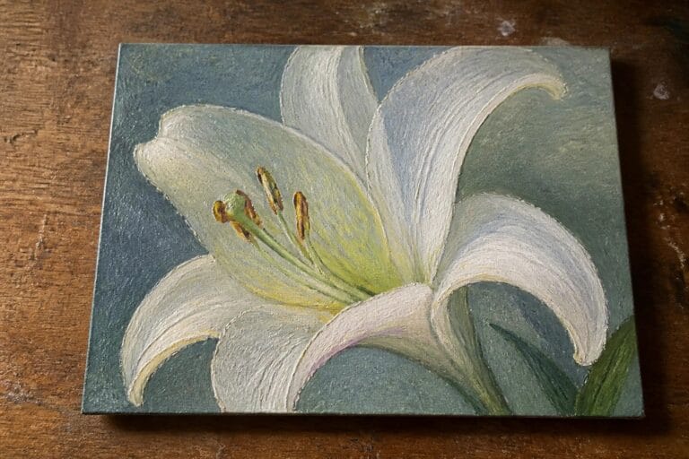 White lily with yellow stamens on gray canvas atop wooden table.