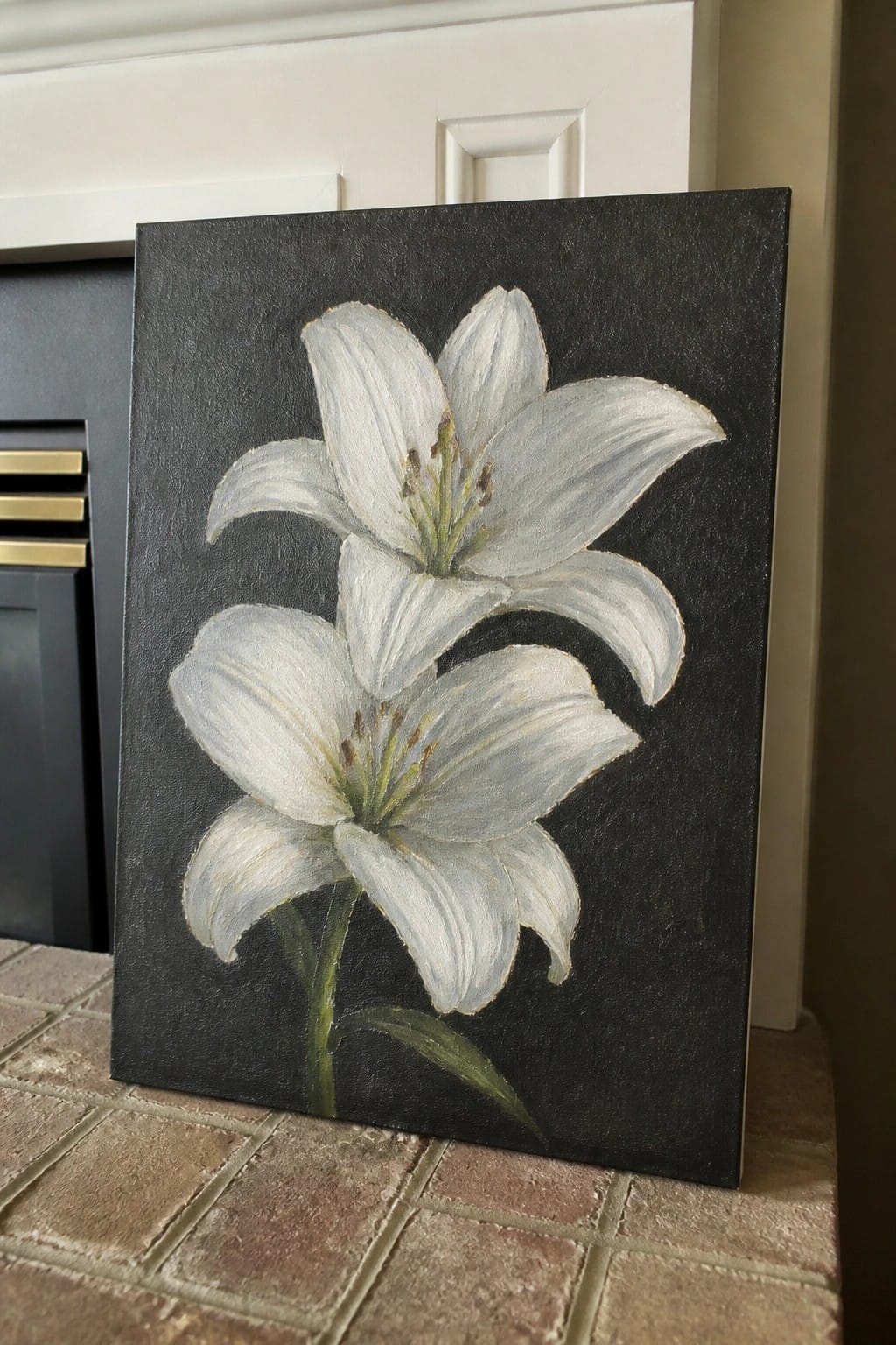 Two white lily flowers with green stems and leaves painted on a black canvas.