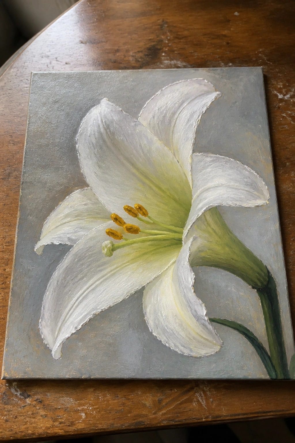 White lily with yellow stamens on gray canvas atop wooden table.