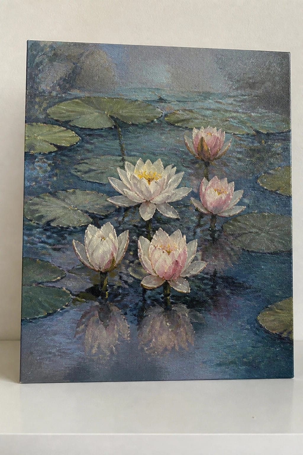 An oil painting of several pink and white water lilies floating among green lily pads on dark blue water with visible reflections of the flowers.