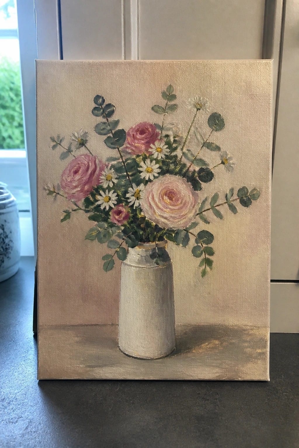 Painting of pink roses and white daisies in a white vase with green foliage