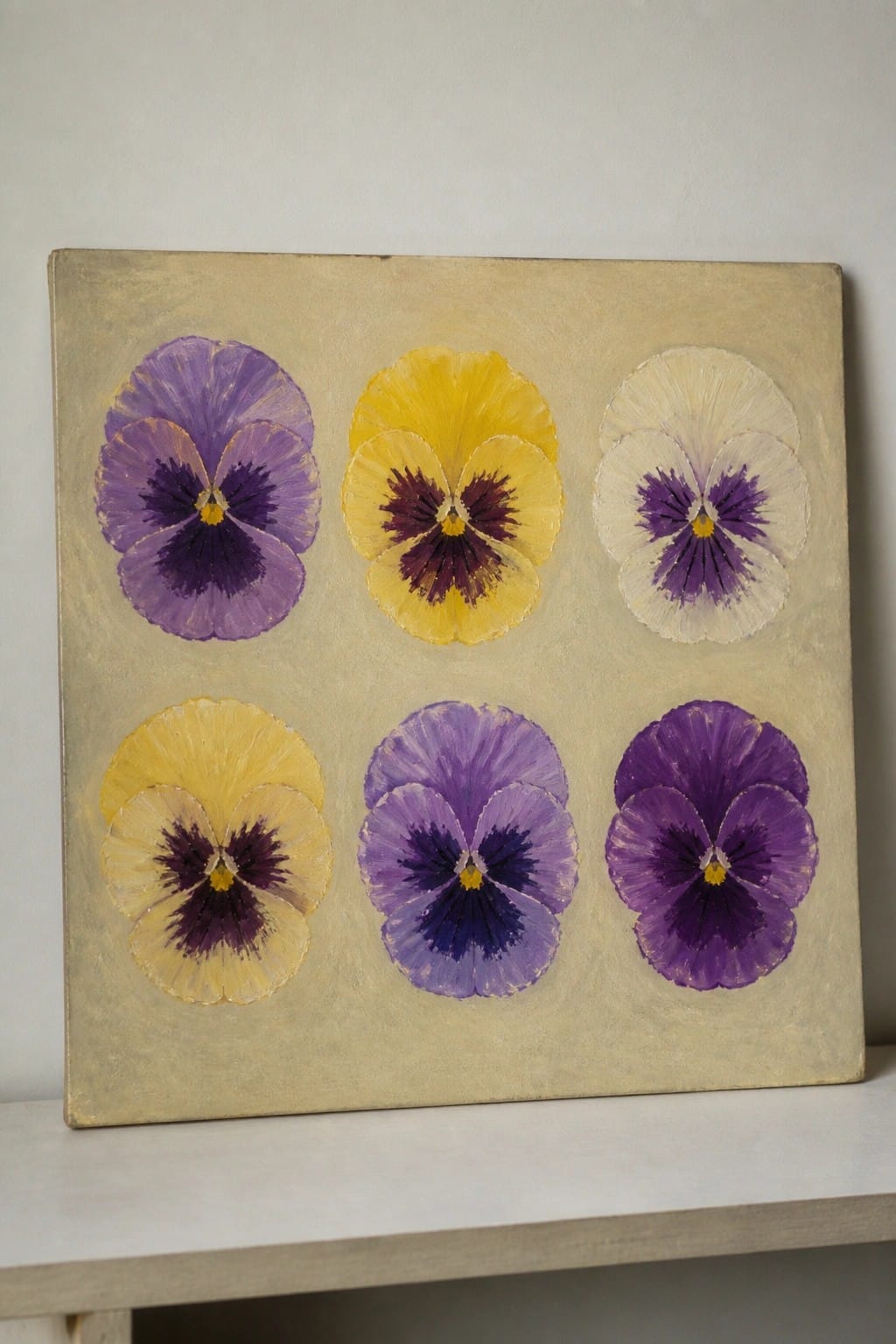 Six pansy flowers in purple, yellow, and white painted on beige canvas.