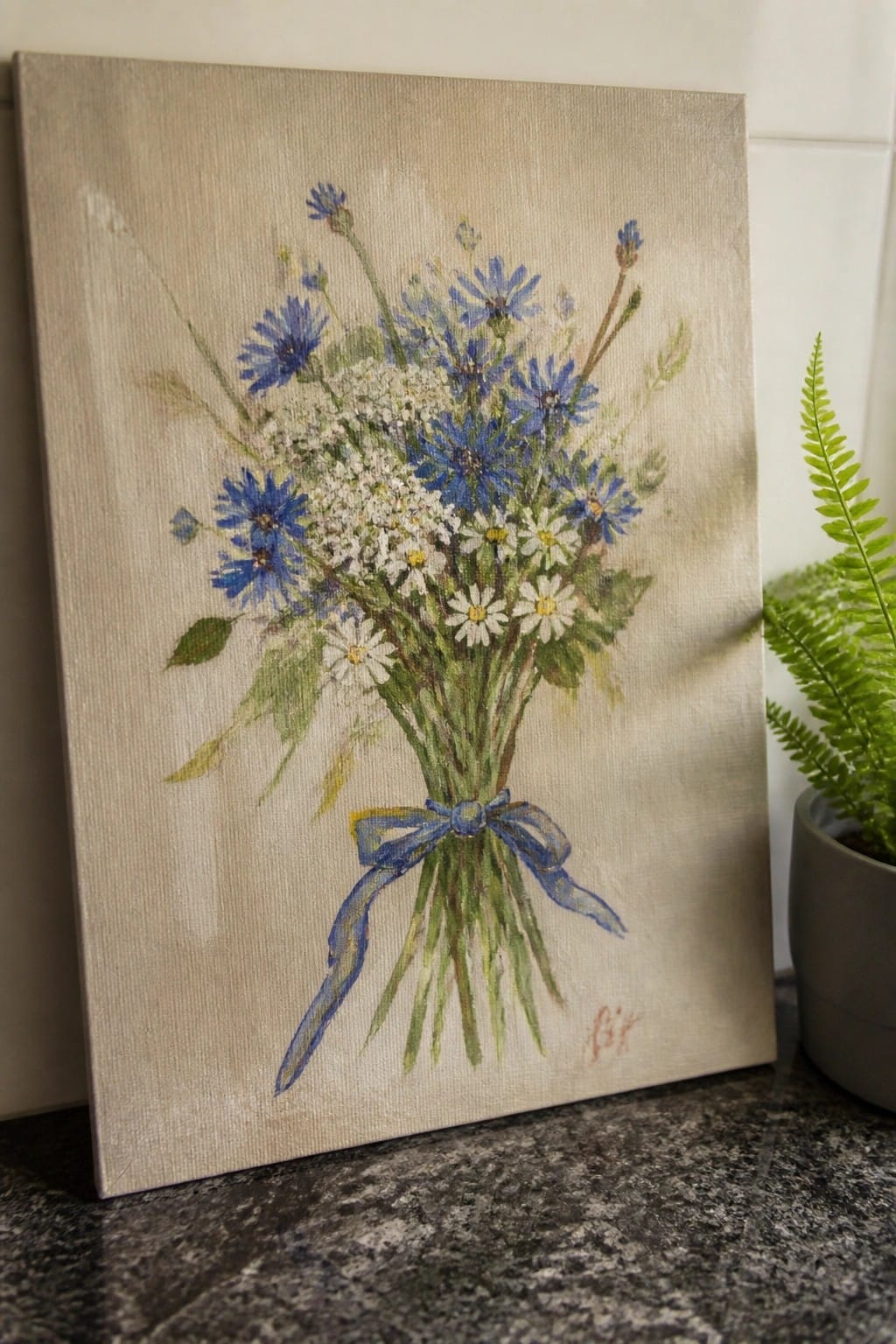 Watercolor painting of blue cornflowers and white daisies tied with blue ribbon.
