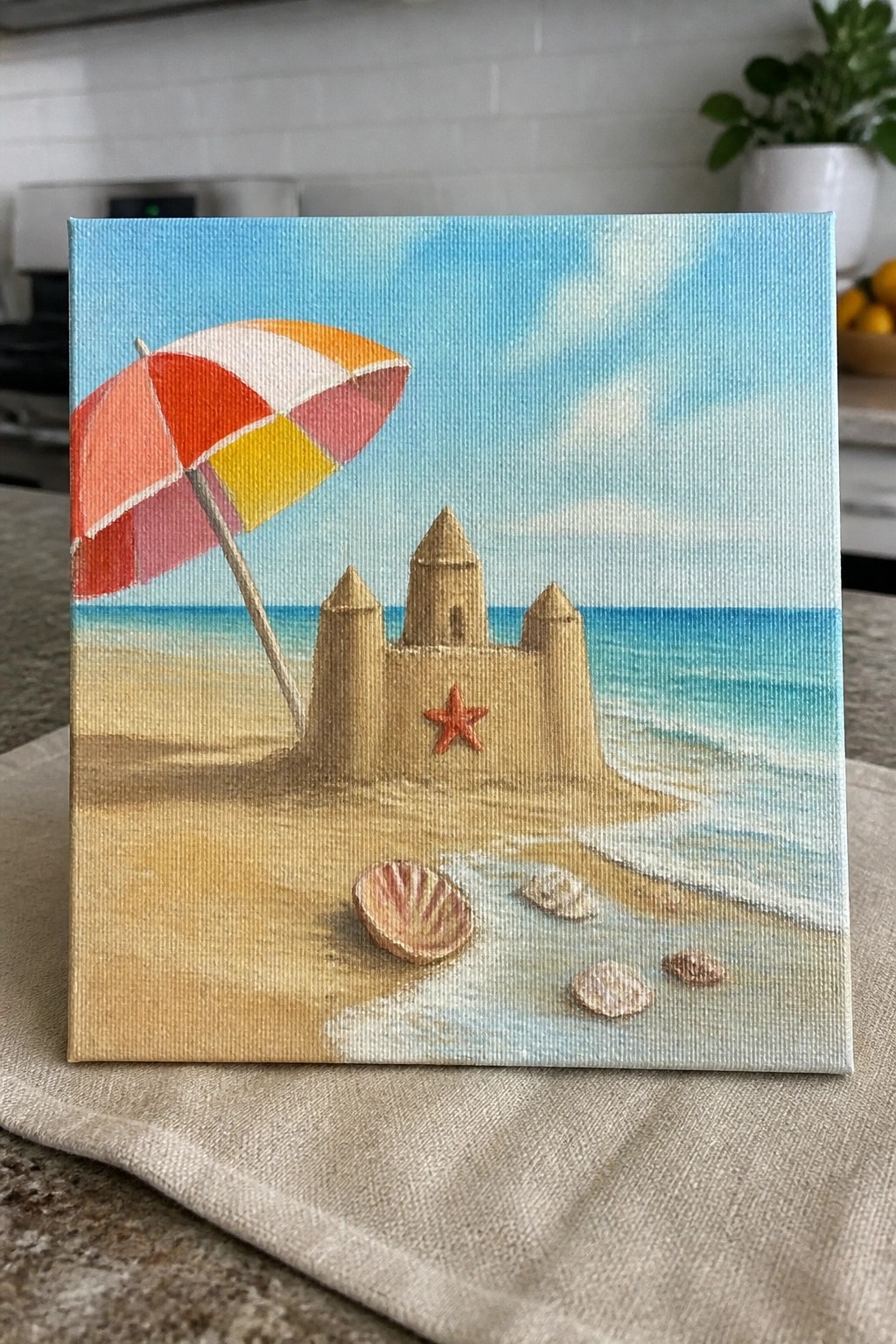 Colorful umbrella beside sandcastle with starfish and seashells on sunny beach