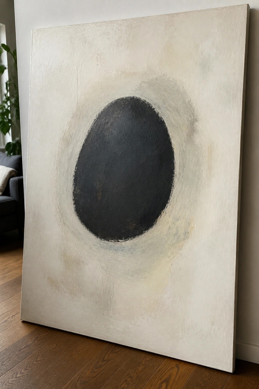 Abstract painting with central black oval on textured off-white canvas in room