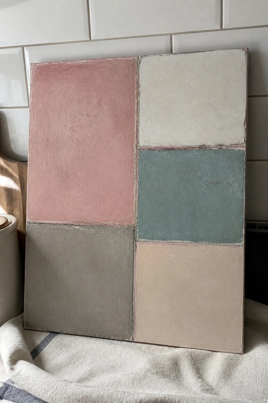 Pastel abstract painting with pink, white, teal, gray, and beige sections against tiles.