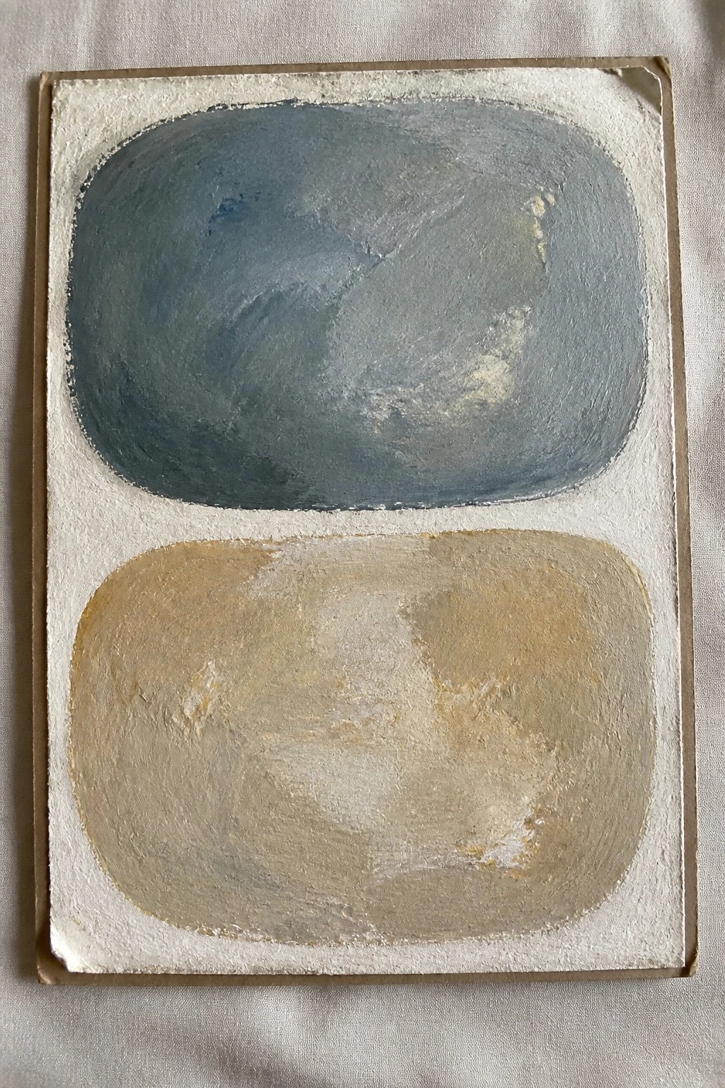 Abstract painting with blue-gray oval above beige oval on white textured background.