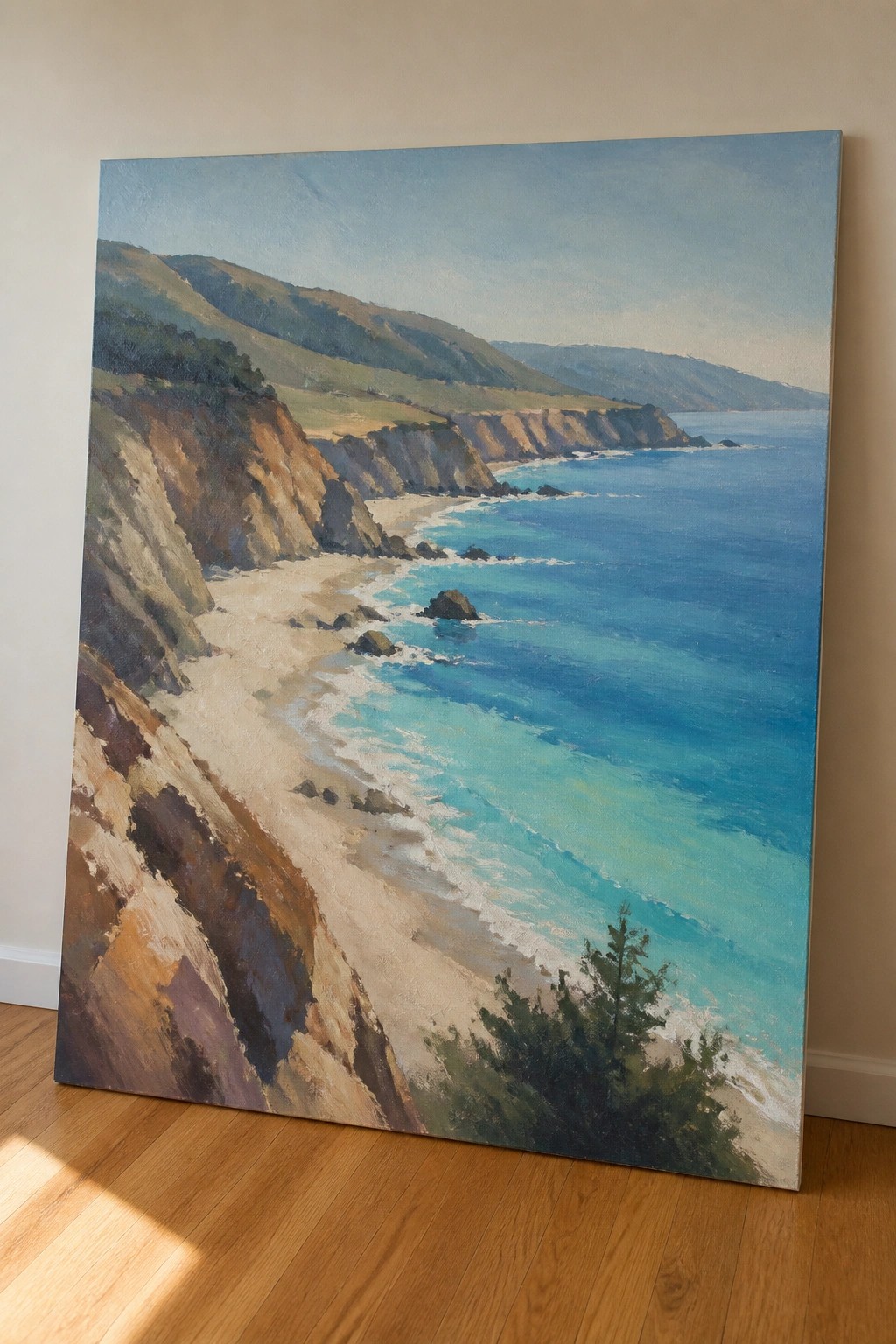 Large coastal painting of turquoise ocean, cliffs, and beach leaning on wooden floor
