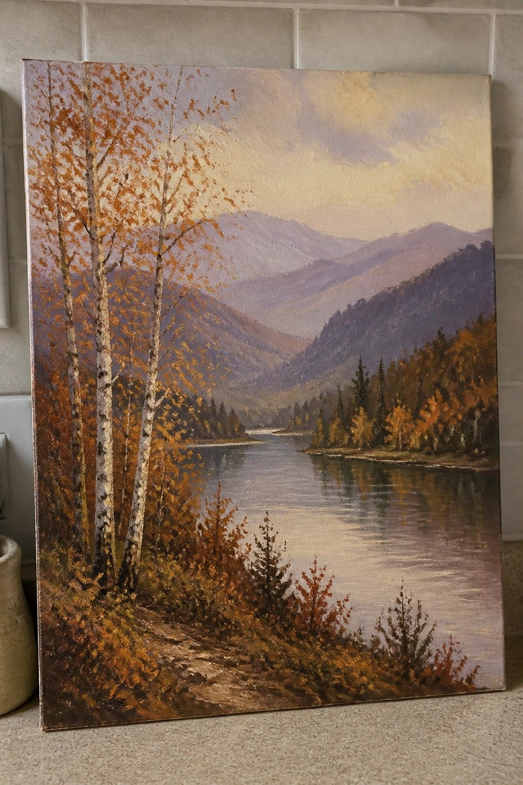 Autumn landscape painting with orange birch trees beside reflective river and mountains