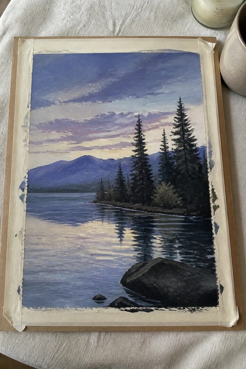 Watercolor painting of twilight lake with pine trees, mountains, and purple-pink sky reflections.