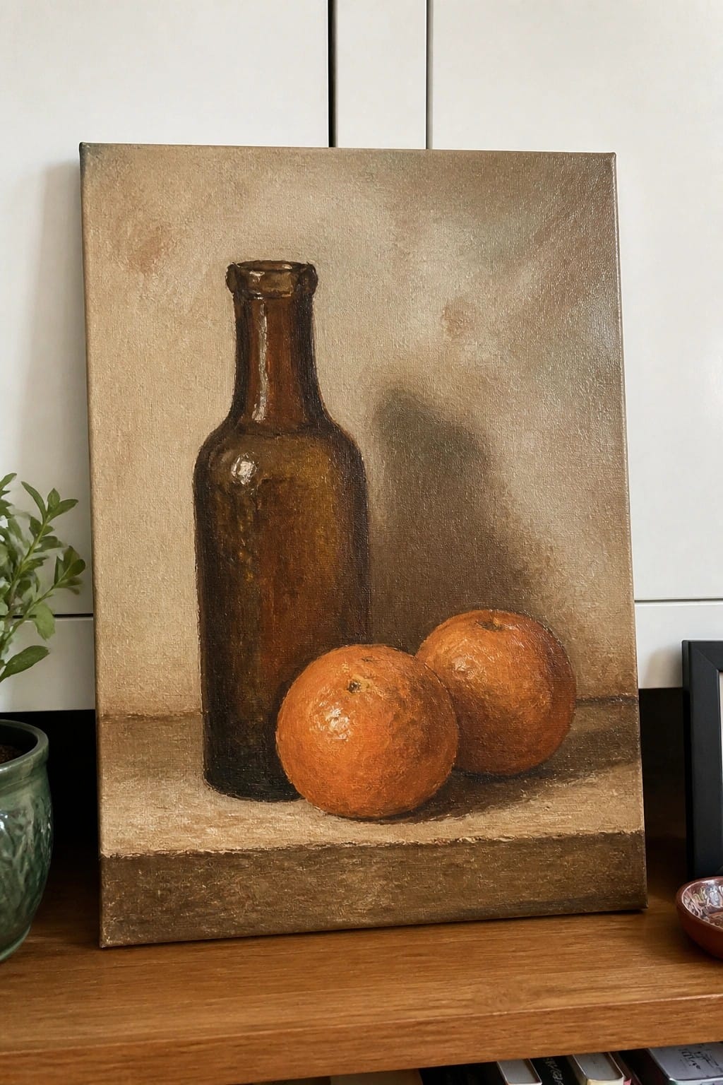 Still life painting of brown bottle and two oranges on earthy surface
